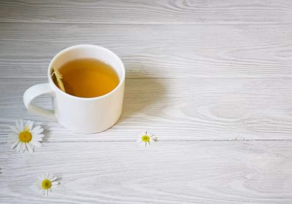Secangkir teh camomile hangat di atas meja terang, simbol relaksasi malam